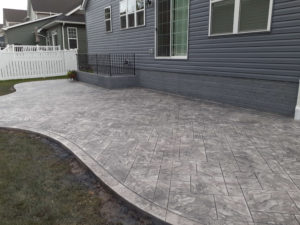 After photo of gray house with new stamped concrete patio.